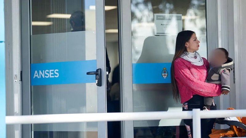 Mujer con bebé en brazos en la puerta de ANSES.