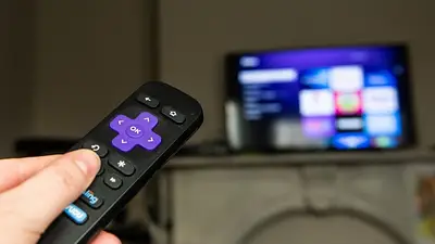 Mano sostiene control y apunta a televisor Mano sostiene control y apunta a televisor