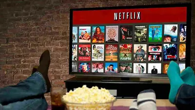 Pies sobre la mesa, pochoclos y televisor con Netflix Pies sobre la mesa, pochoclos y televisor con Netflix