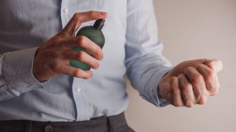 hombre poniendose perfume.