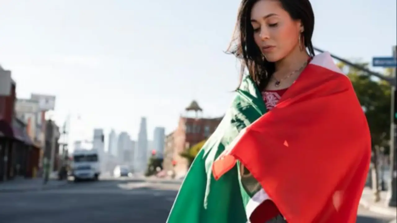 Mujer envuelta en bandera de México en ciudad urbana representando el Mundial 2026