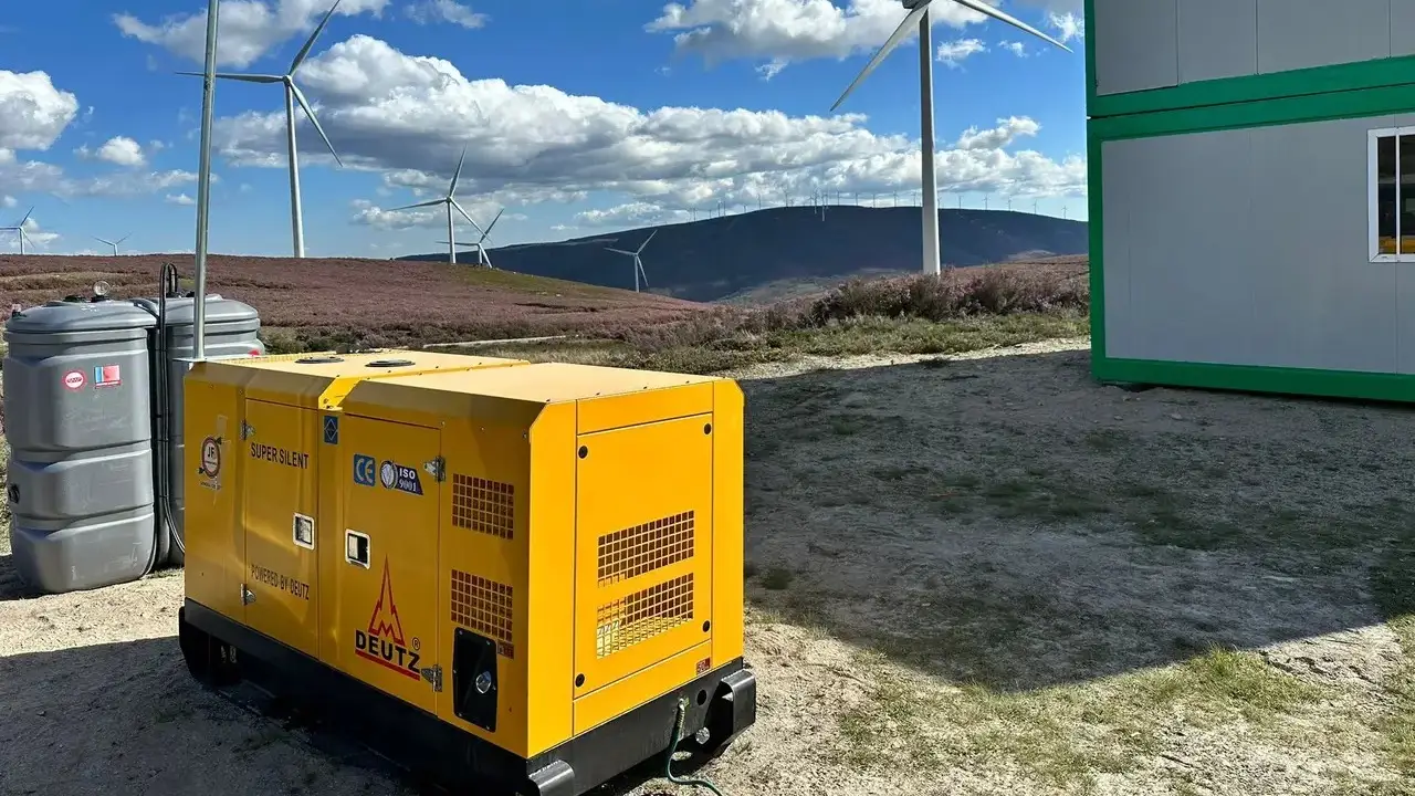 Generador eléctrico amarillo en parque eólico con aerogeneradores al fondo