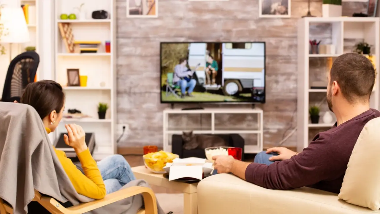 Dos personas ven televisor en su living.