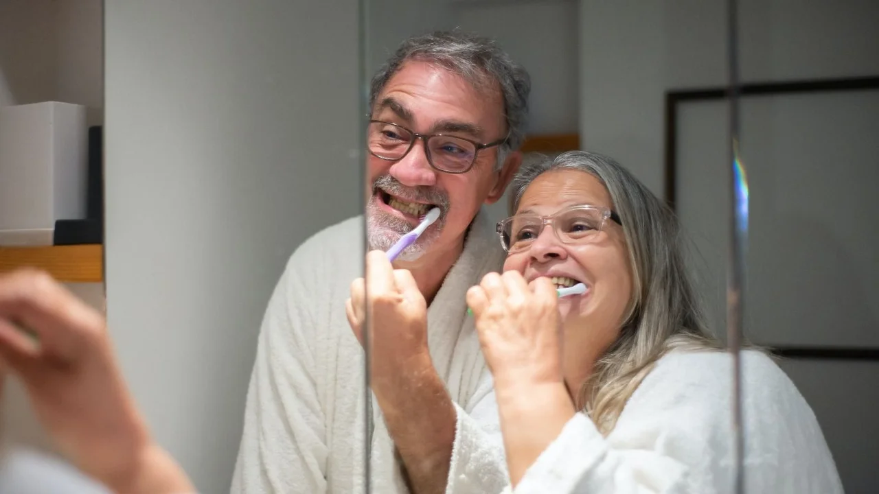 dos personas se cepillan los dientes