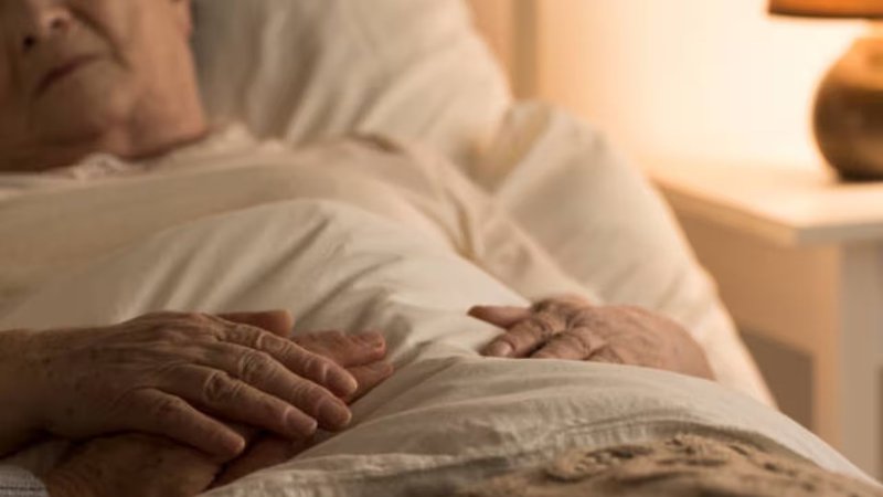 Anciano recostado en una cama.