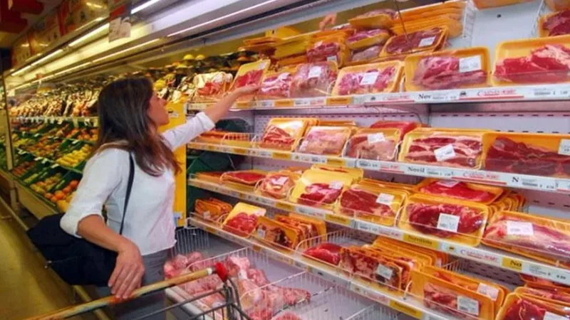mujer comprando carne en el supermercado.
