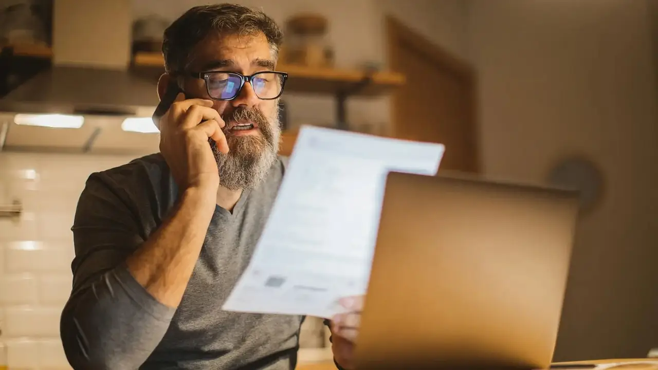 Hombre hablando por teléfono con una factura en la mano