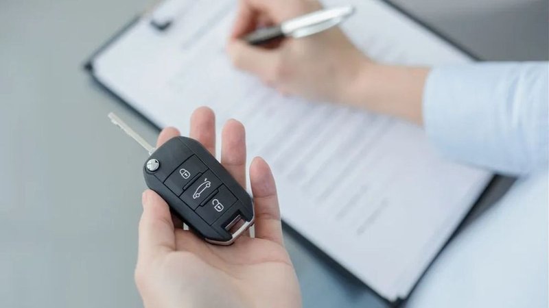 Persona con llave de auto firmando papeles.