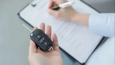 Persona con llave de auto firmando papeles. Persona con llave de auto firmando papeles.