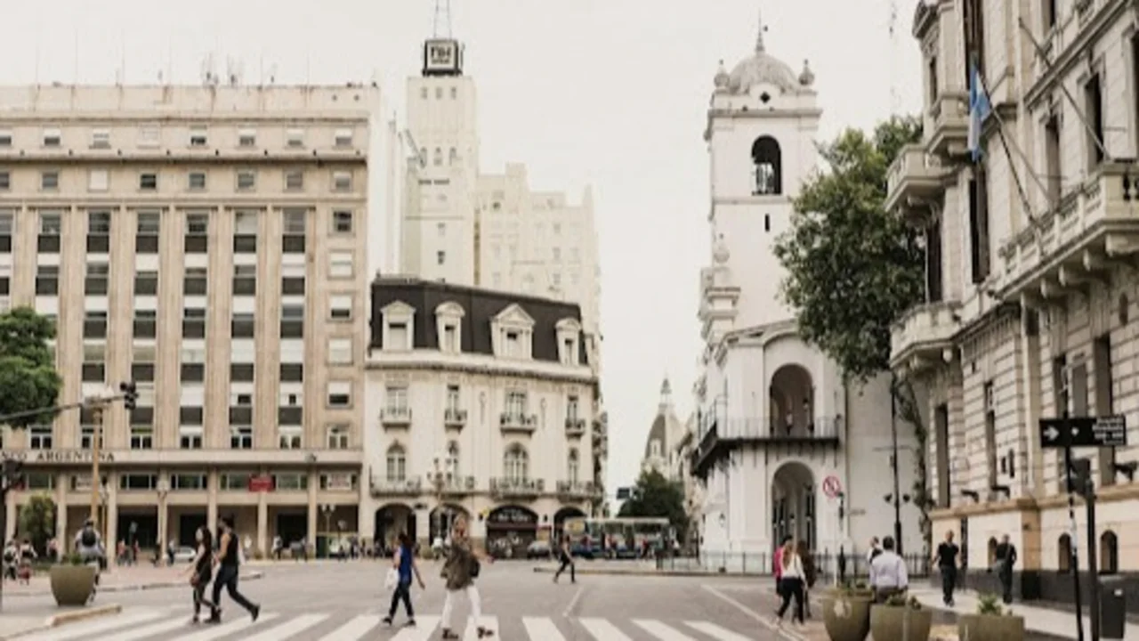 Vista de la Plaza de Mayo, Buenos Aires, con peatones cruzando y edificios históricos al fondo