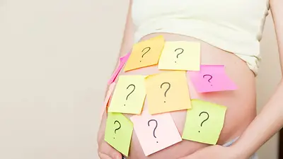 Una mujer embarazada con papeles con signos de pregunta en la panza Una mujer embarazada con papeles con signos de pregunta en la panza