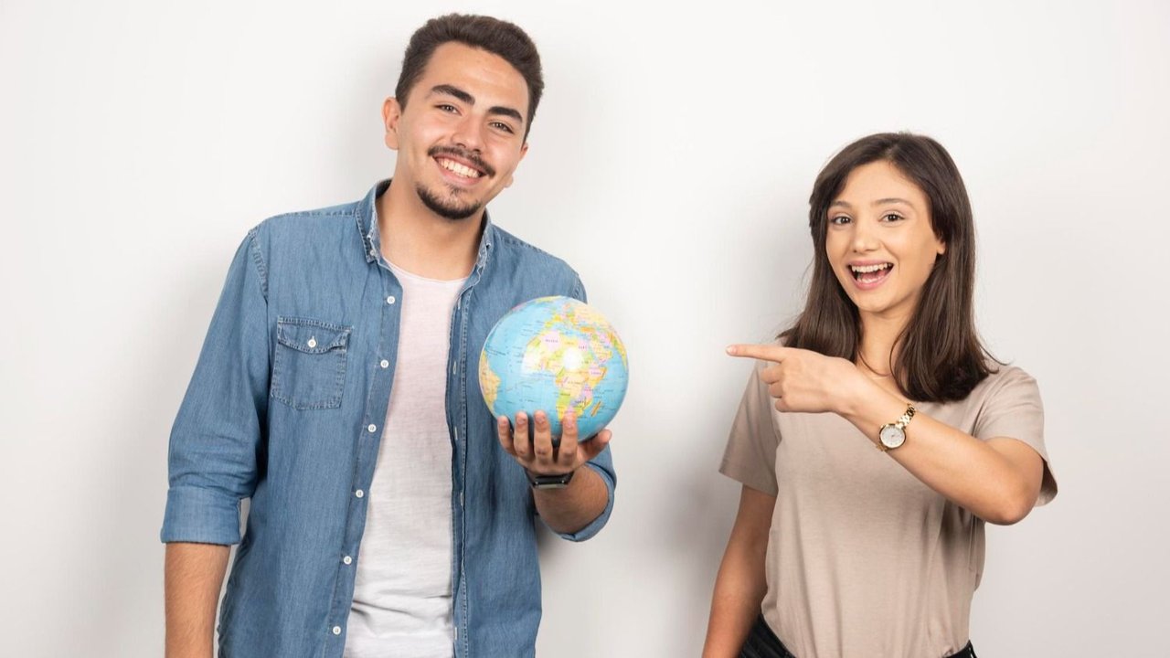 Un chico sosteniendo un globo terráqueo junto a una chica