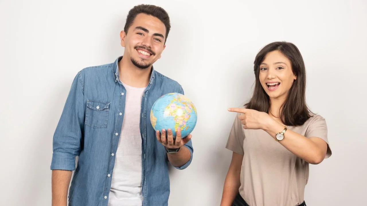 Un chico sosteniendo un globo terráqueo junto a una chica