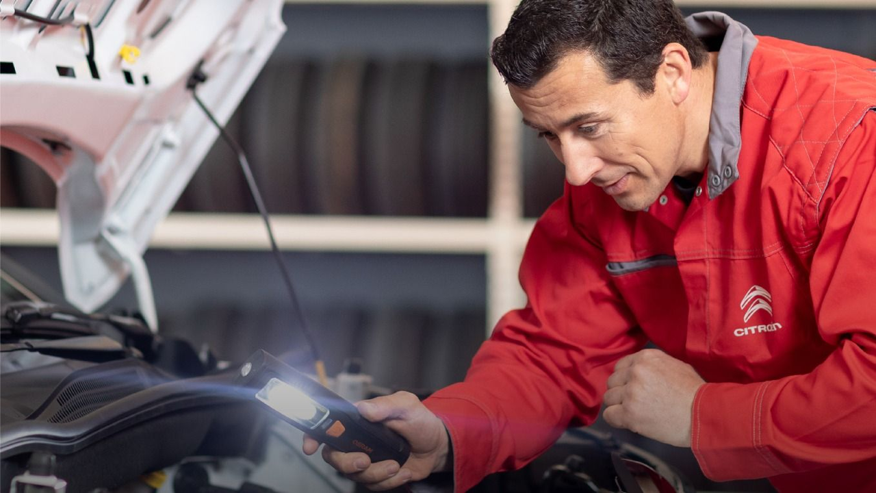 Mecánico con ropa de Citroen revisando un auto