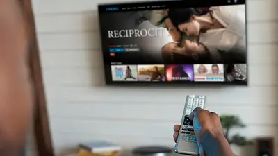 Persona usa un control remoto frente a una Smart TV con contenido de streaming Persona usa un control remoto frente a una Smart TV con contenido de streaming