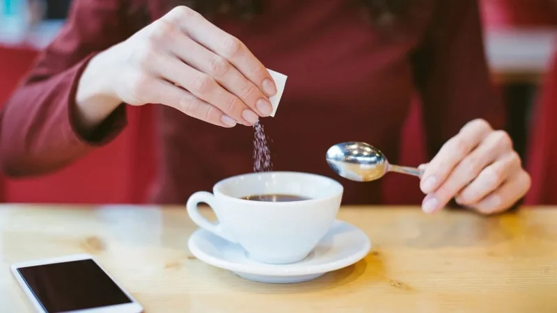 Persona tomando café con edulcorante