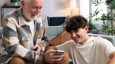 Un hombre mayor y un joven viendo un celular Un hombre mayor y un joven viendo un celular