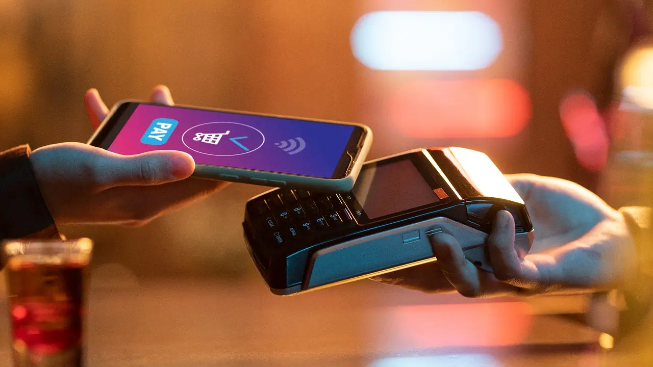     Persona realiza un pago digital con celular en una terminal de cobro