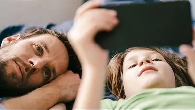 Niño utilizando un dispositivo junto a su padre Niño utilizando un dispositivo junto a su padre