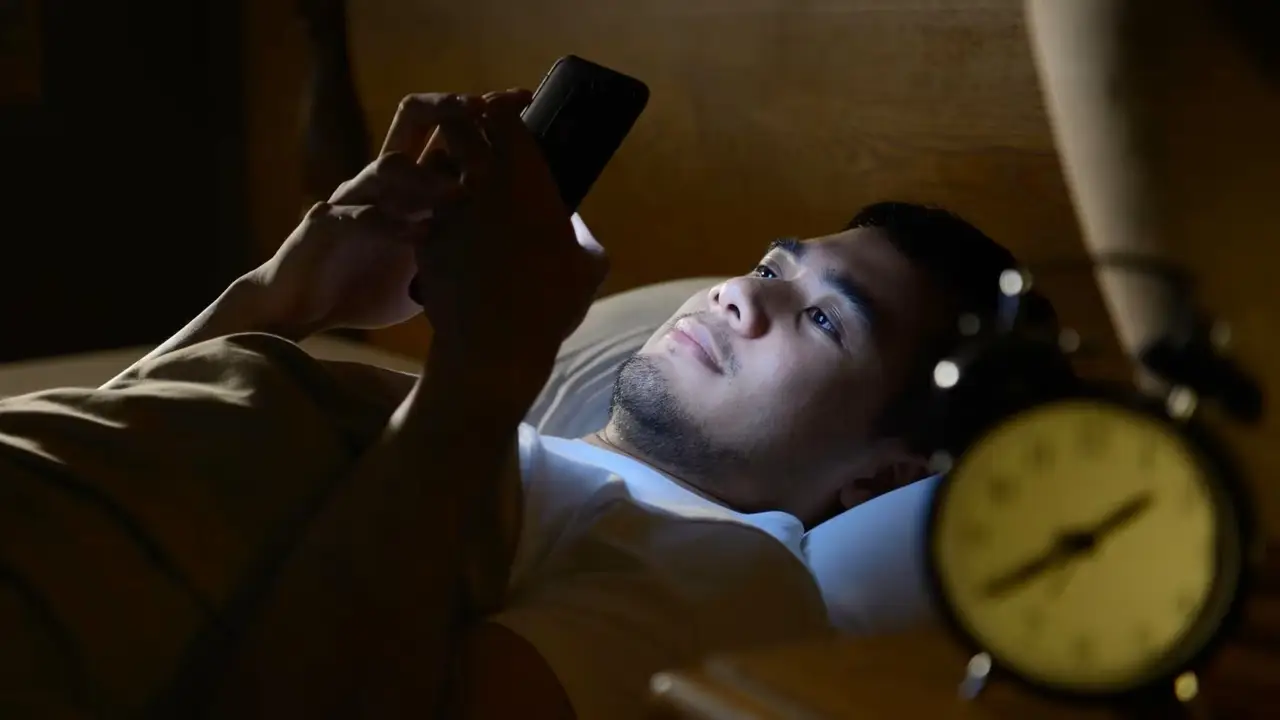 Persona usando el celular en la cama.