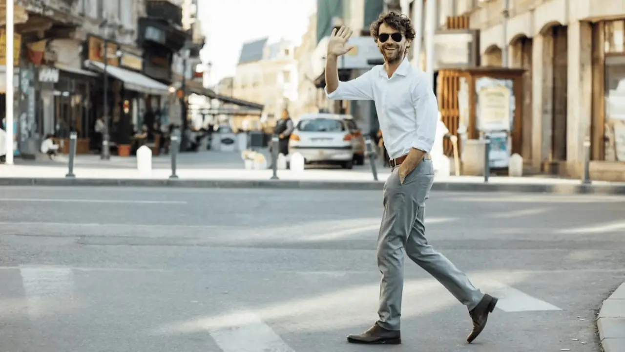 Persona saludando al cruzar la calle.