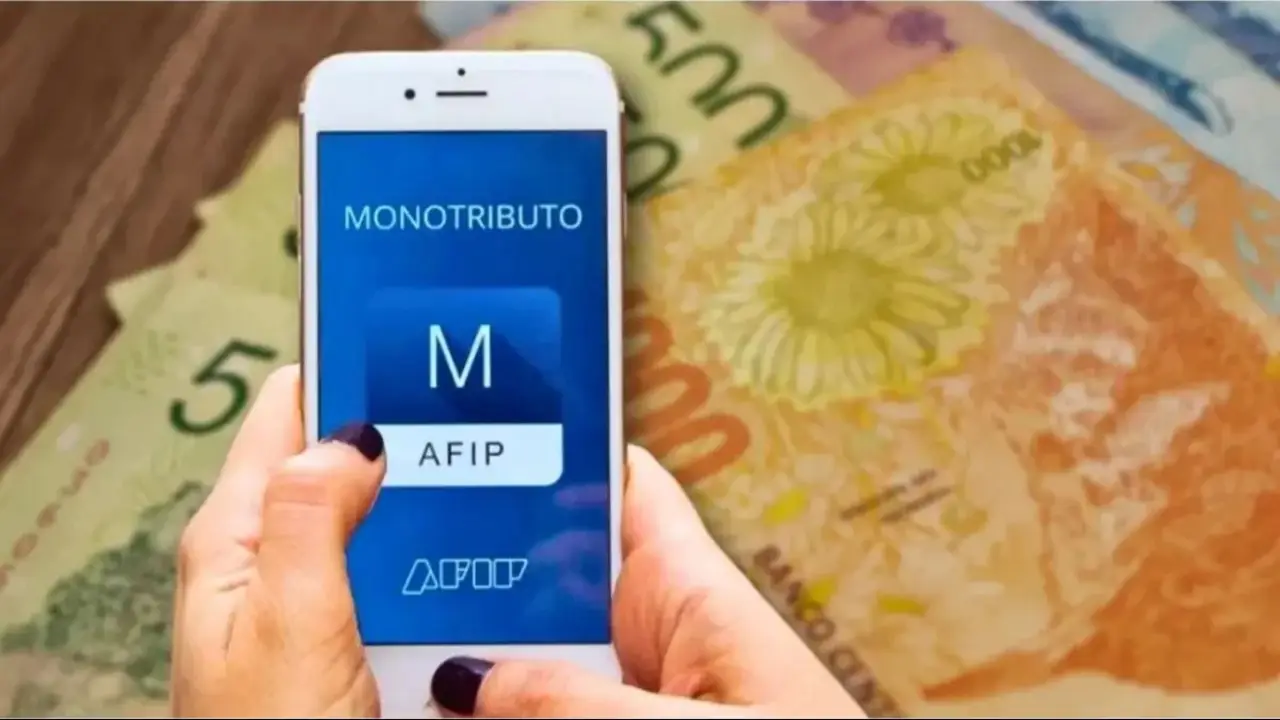 Web del monotributo de ARCA en un celular con billetes de fondo.