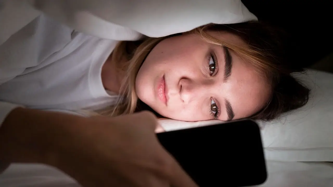 Una chica con el celular en la cama