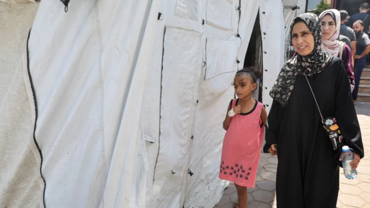 Una madre intenta evitar que su hija vea las heridas de su cabeza en la destrozada Gaza
