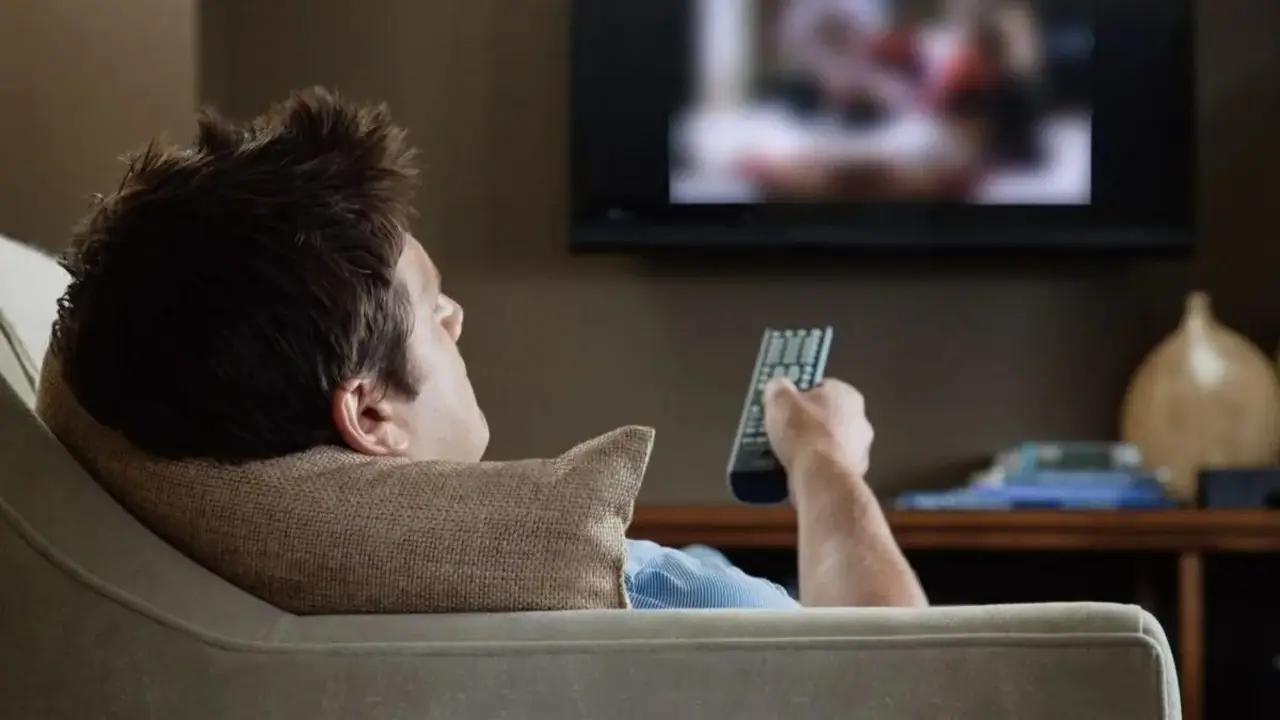 Hombre ve televisión en living