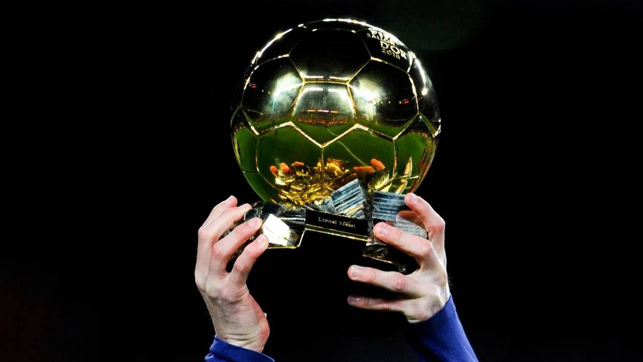 Las manos Lio Messi sostienen su Balón de Oro, premio a mejor jugador de futbol