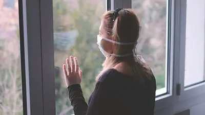 Una mujer con barbijo haciendo cuarentena en su casa Una mujer con barbijo haciendo cuarentena en su casa