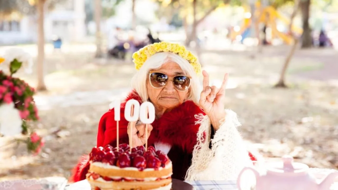 Un mujer con una torta de cumpleaños con el 100
