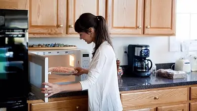 Mujer utilizando un microondas. Mujer utilizando un microondas.