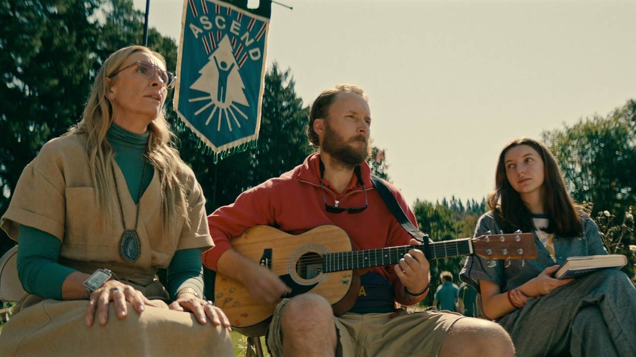 Elenco de serie de Netflix. Tres actores con una guitarra en un día con mucho sol, en el bosque