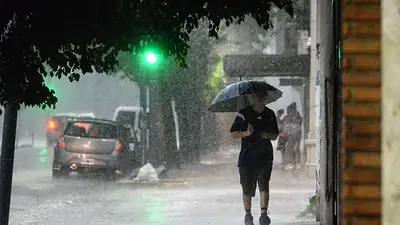 Persona caminando bajo la lluvia con un paraguas Persona caminando bajo la lluvia con un paraguas