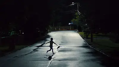 Niño corre en medio de una calle en la noche para película Niño corre en medio de una calle en la noche para película