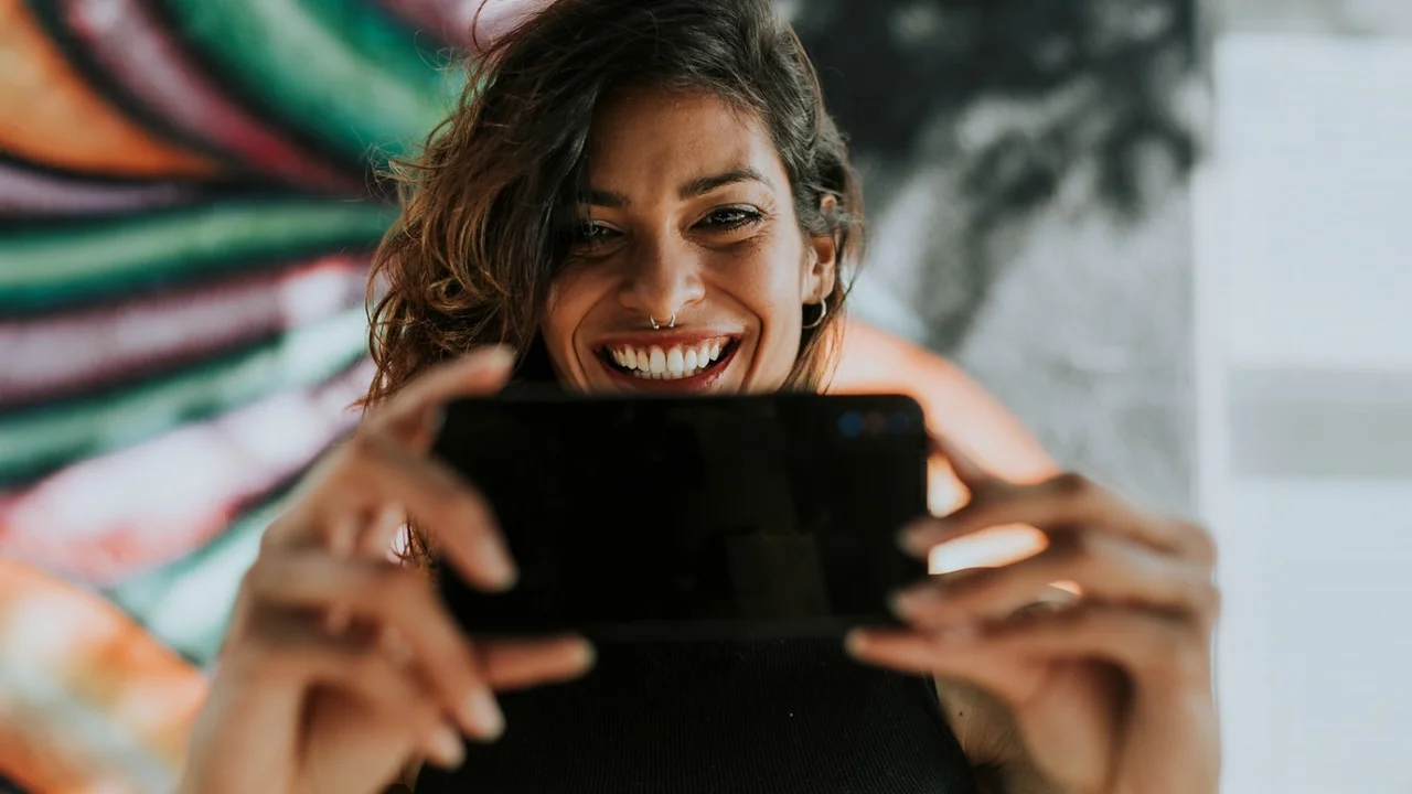 Mujer utiliza un celular como parte del crecimiento del entretenimiento digital en México