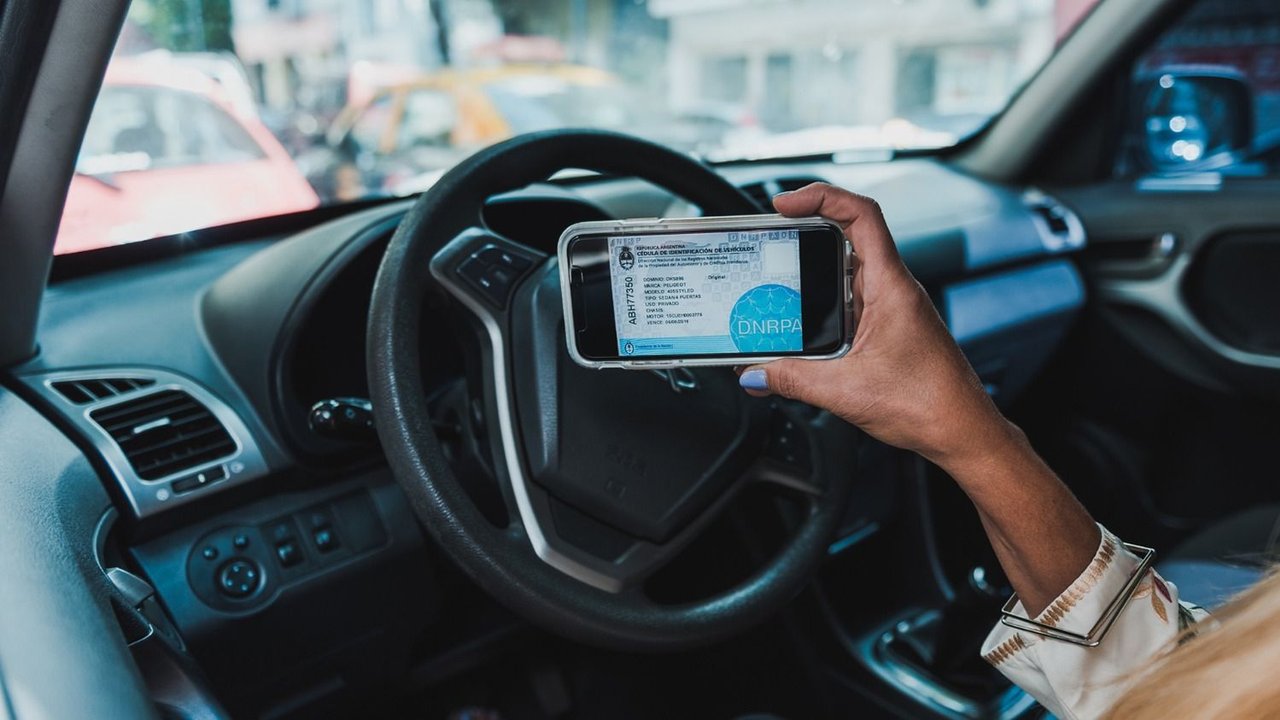 Conductor mostrando su título automotor digital en su teléfono celular 