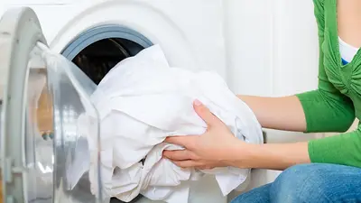 Mujer lavando ropa blanca en el lavarropas de su hogar Mujer lavando ropa blanca en el lavarropas de su hogar