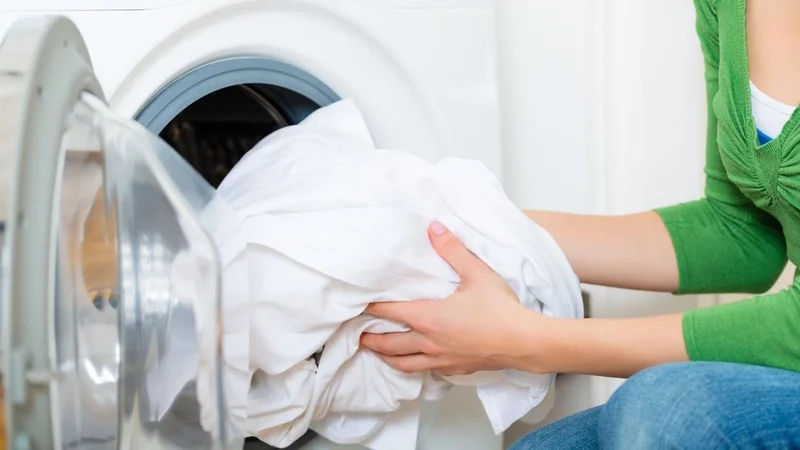 Mujer lavando ropa blanca en el lavarropas de su hogar 