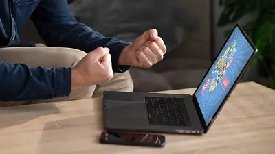 Hombre celebrando frente a su laptop tras ganar en un juego online Hombre celebrando frente a su laptop tras ganar en un juego online