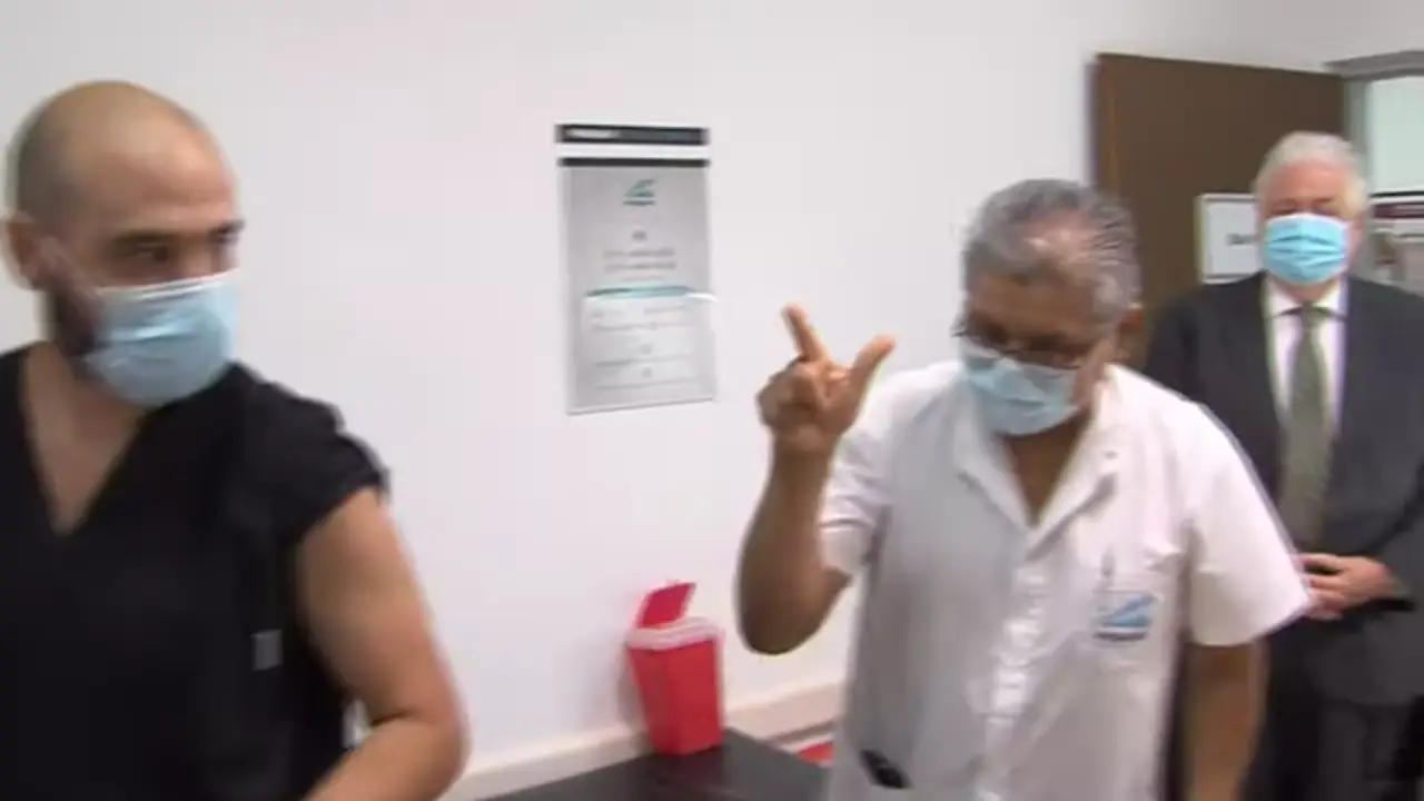 Un enfermero hizo los dedos en V con el índice y el pulgar durante el primer día de vacunación.